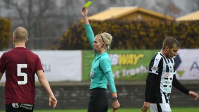 Fotbollsdomaren Lina Lehtovaara visar ett gult kort.