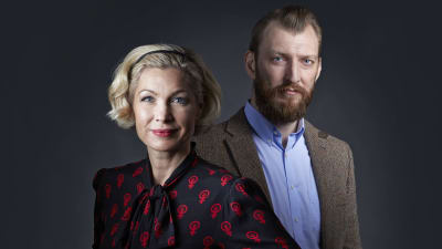 Porträttbild av Anna-Karin Wyndhamn och Ivar Arpi som poserar och tittar in i kameran, i en mörklagd studio. 