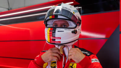 Sebastian Vettel pysslar med sin hjälm.