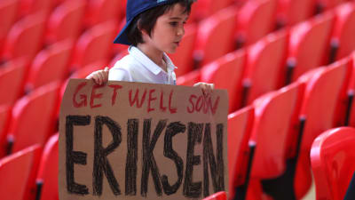 En pojke håller upp en skylt med texten "Get well soon Eriksen" där han står på läktaren under matchen mellan England och Krotatien.