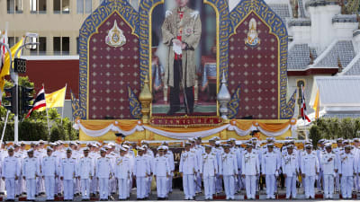 Äldre tjänstemän står utanfär palatset i Bangkok under den kungliga ceremonin.