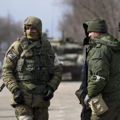 Tre soldater tittar på varandra. De är klädda i utrustning och bär vapen.