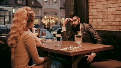 Man och kvinna vid restauramgbord, mannen ser skeptisk ut