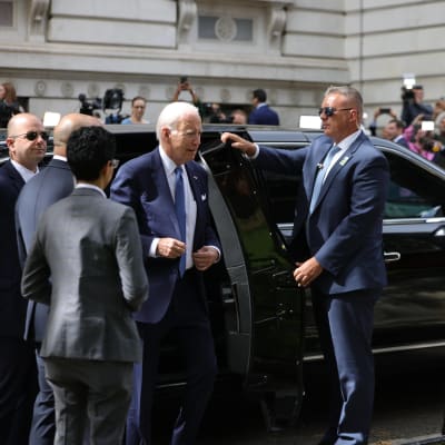 Joe Biden astuu ulos autosta. Molemmilla puolilla on turvamiehiä.