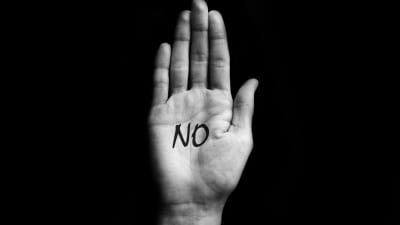 Hand med ordet "No" skrivet i handflatan. 