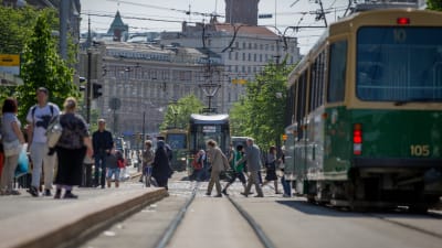 Raitiovaunukiskot ja raitiovaunuja jalankulkijoiden joukossa Helsingissä kesällä.