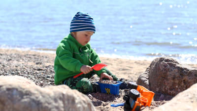 Ett barn leker i sanden.