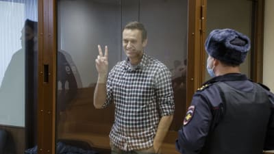 Den ryska oppositionsledaren Aleksej Navalnyj visar segertecknet i rätten