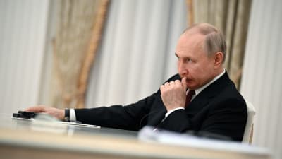 Vladimir Putin sitter vid ett bord.