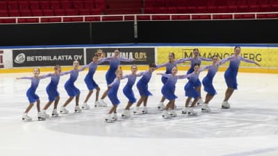 14 unga flickor i ljusblå klänningar skrinner i tre rader på isen.