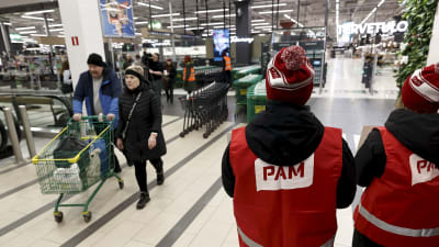 Strejkvakter med texten PAM på ryggen vid en stormarknad i Helsingfors.