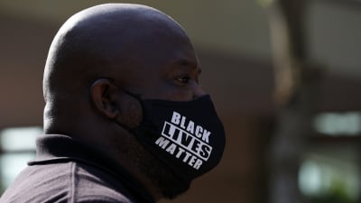 En man bär en skyddsmask med texten Black lives matter.