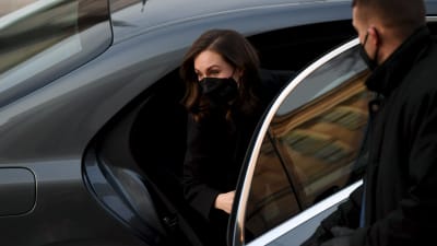 Statsminister Sanna Marin (SDP) stiger ur en grå bil. Hon har ett svart munskydd på sig.