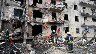 Brandmän röjer bort skrot vid en förstörd höghusbyggnad i Kiev.