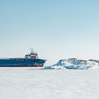 Containerfartyg bland is och snö utanför Hangö, personer går på isen.