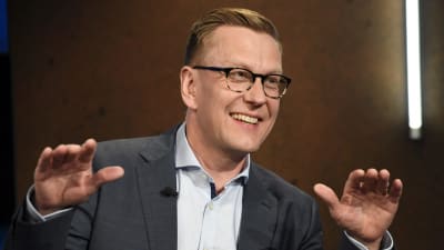Atte Jääskeläinen har glasögon och rågblont hår kammat åt sidan. Han ser glad ut och gestikulerar.