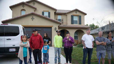 Grannar står utanför familjen Turpins hus i Perris, Kalifornien, där polisen grep föräldraparet och tog om hand syskonskaran på 13 personer. 