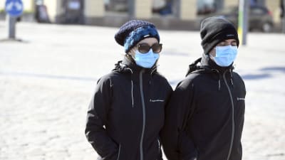 Ett par med munskydd promenerar i Helsingfors centrum.