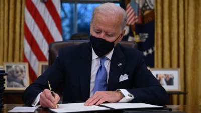 Joe Biden sitter i Ovala rummet i Vita huset och signerat presidentdekret.