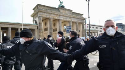 Poliser grep och förde bort en av coronademonstranterna framför Brandenburg Tor i Berlin på lördagen. 