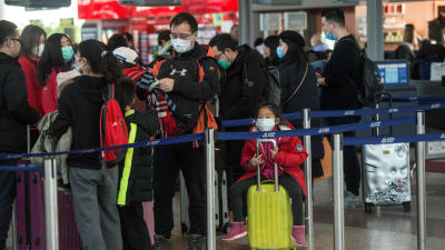 På bilden syns resenärer som köar till flyg på väg till Shangai på en flygplats i Prag.