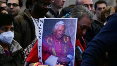 En kvinna som köade till Peterskyrkan på onsdagen bar på påven Benedictus XVI:s porträtt. 