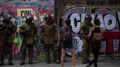 Unga kvinnor skrek åt kravallpolisen under en demonstration mot högerkandidaten Kast i huvudstaden Santiago på lördagen. 
