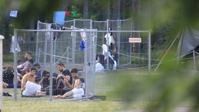 Migranter väntar vid ett stängsel nära den litauiska gränsstaden Kapciamiestis.