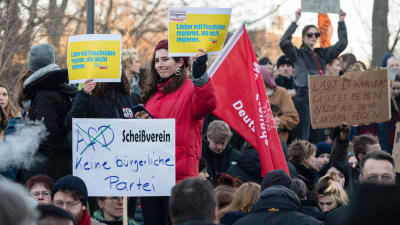 Personer håller upp plakat och demonstrerar i Tyskland. 