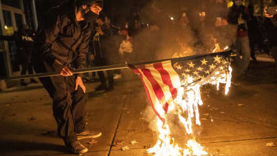 Den amerikanska flaggan i lågor i nattlig demonstration i Washington.