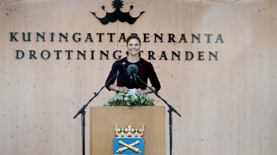 Kronprinsessan Victoria i en talarstol med Lovisa stads vapen på. Bakom kronprinsessan står det Kungingattarenranta Drottningstranden på en paviljong i trä.