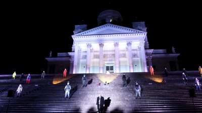 Upplysta Domkyrkan i Helsingfors med skådespelare i Via Crucis på trapporna.