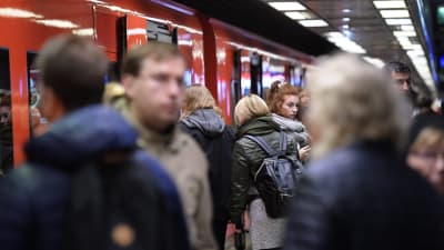 Bild från metrostation under rusningstid. Flera personer rör sig ut och in från metron.