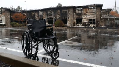 Efterlämnad rullstol i regn framför brandruiner i Paradise, Kalifornien