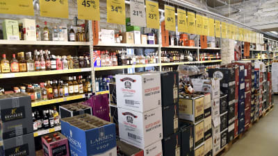 Bild från en alkoholbutik. På marken står lådor med vin och hyllorna i bakgrunden är fyllda med sprit.