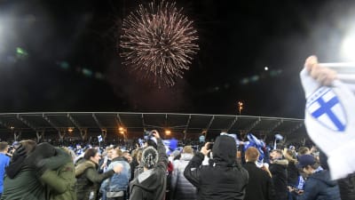 Fans som står på fotbollsplan och ser på fyrverkerier samtidigt som de firar Finlands vinst i matchen mot Liechtenstein som tog dem till EM 2020.