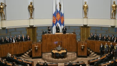 Högtidlig invigning i riksdagssalen, med president och talmän framför Finlands flaggor