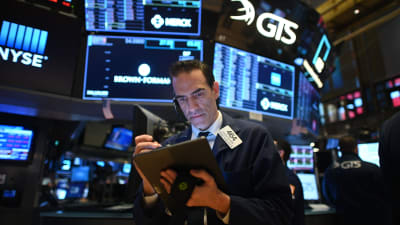 En man i kostym står framför en mängd skärmar på New York-börsen den 19 mars 2020.