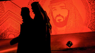 Saudier promenerar under ett porträtt av Prins Mohammad bin Salman