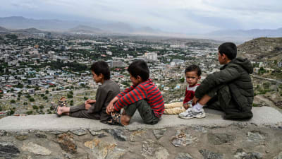 Barn sitter på en mur och tittar ut över Kabul 17.5.2020