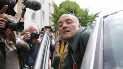 Dominic Cummings stiger in i sin bil omgiven av pressfotografer