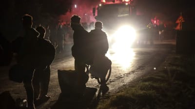 Fyra personer står i ljuset av lyktorna från en brandbil