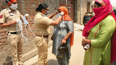 Kvinnor får munskydd inför en taxiresa till ett vaccineringscentrum