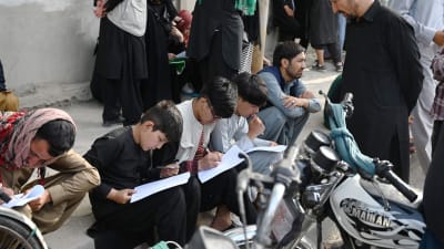 Afghaner fyller i dokument för att kunna lämna landet. utanför den brittiska och kanadensiska ambassaden i Kabul 19.8.2021