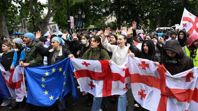 En grupp unga människor håller upp Georgiens och EU:s flaggor.
