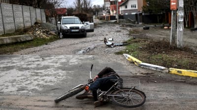 Vy från Butja i Ukraina där en äldre man fallit omkull med sin cykel och ligger död på gatan.