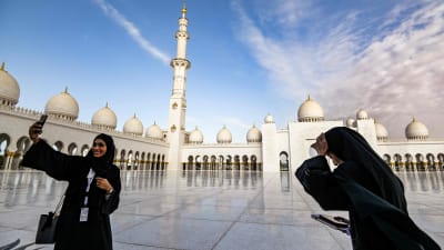 Muslimska kvinnor tar "selfies" framför moskén i Abu Dhabi inför påvens besök.