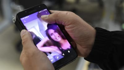 En person tittar på sin telefon på en skärmdump som spridits på social medier. Där kan man se hur statsminister Sanna Marin festar på en privat tillställning.