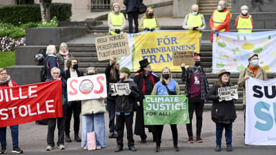 Människor demonstrerar utanför Ständerhuset 8.9.2021. De håller upp plakat med texter för klimatet.