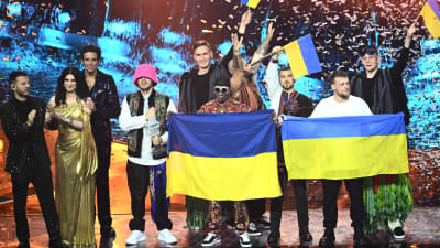 Personer som står på en scen med ukrainska flaggor i händerna.